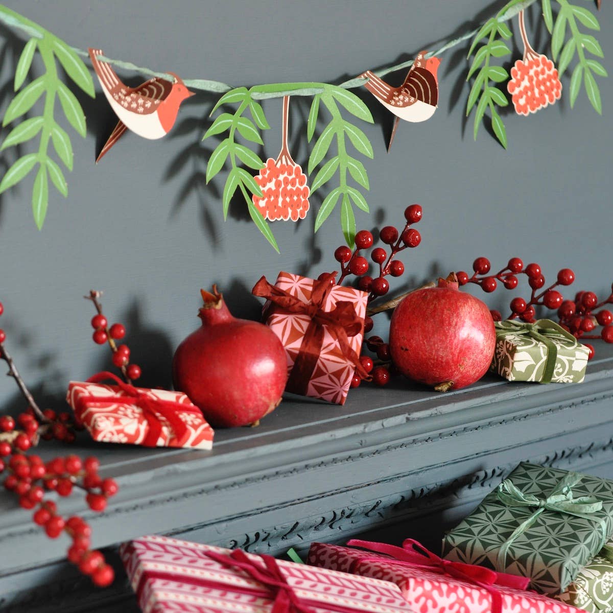 Cambridge Imprint paper robin and rowan garland hung above a grey mantel with wrapped Christmas gifts