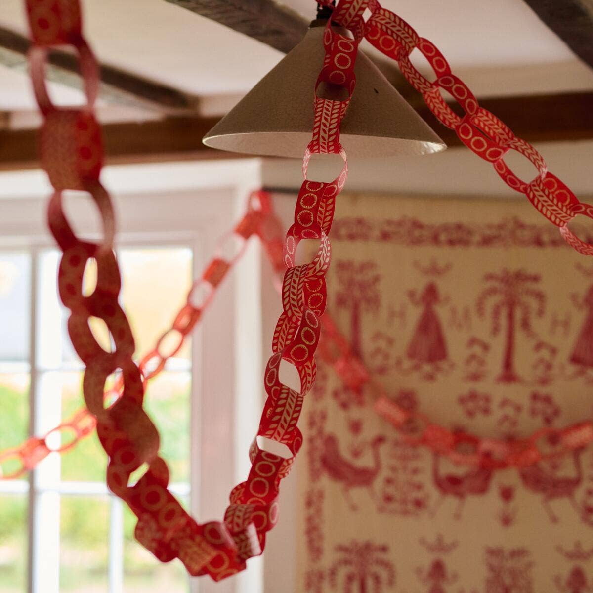 Finished red patterned paper chains draped across a room beneath wooden ceiling beams