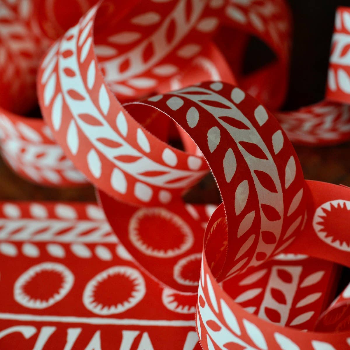 Close-up of linked red and cream paper chain loops with leaf and circle patterns
