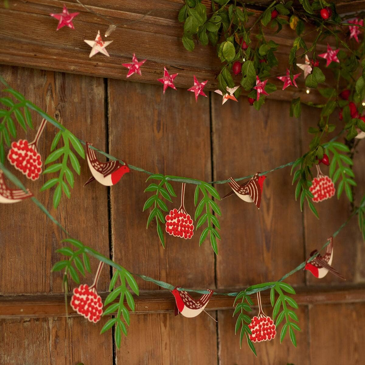 Robin and rowan paper garland draped across wooden panelling beneath a separate star garland