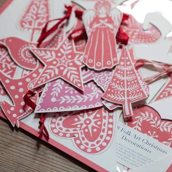 Close-up of patterned folk-art Christmas card ornaments with hearts, stars, an angel and a tree