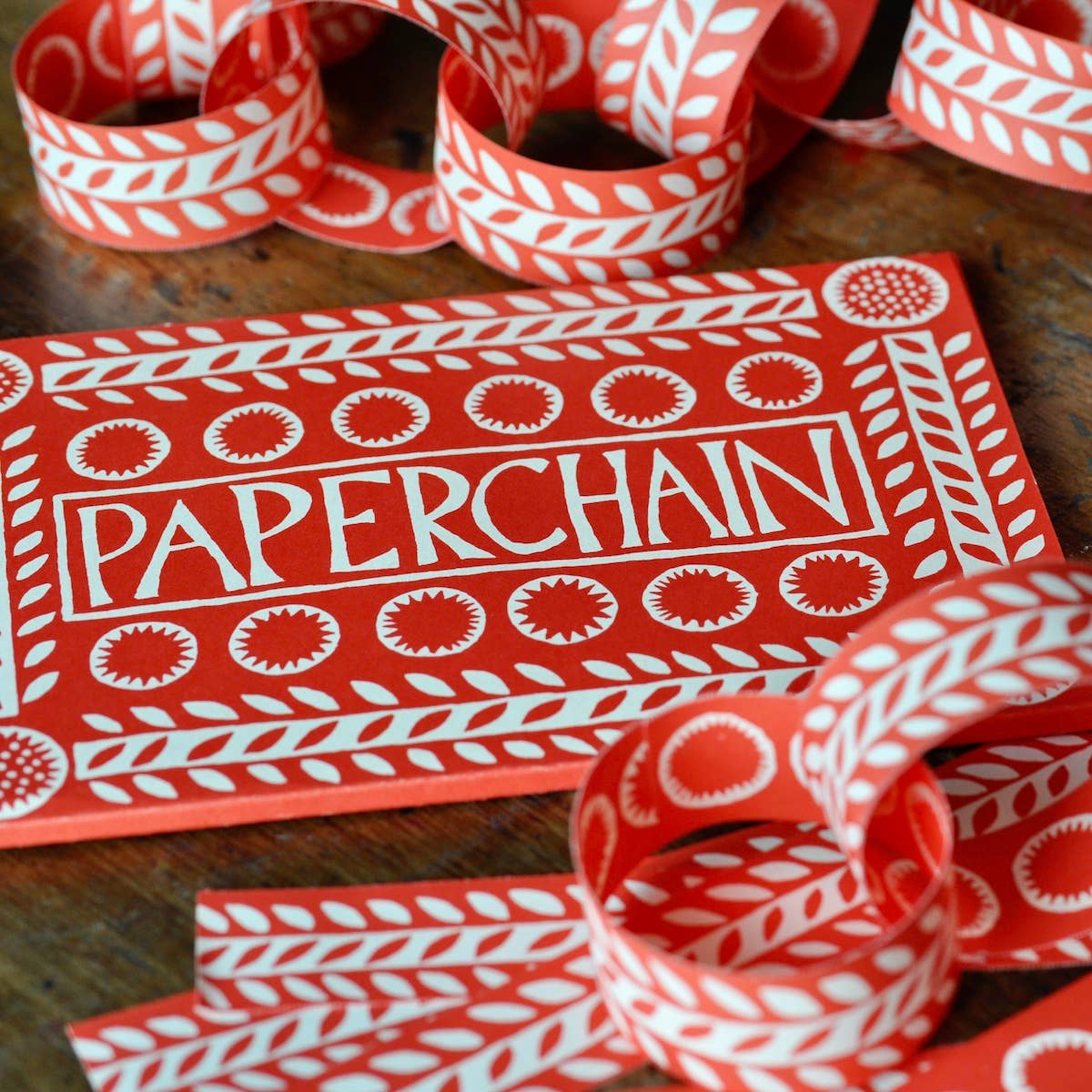 Red and cream patterned paper chain loops and loose strips beside the Cambridge Imprint kit wallet